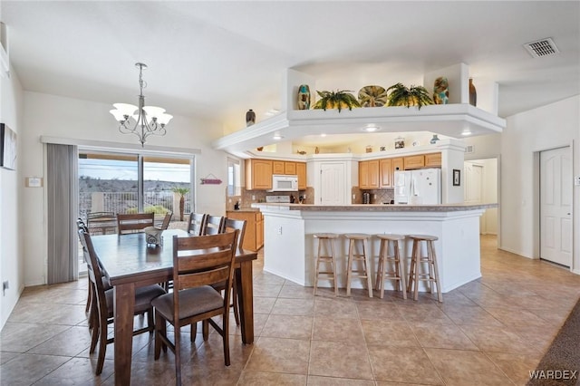 dining space featuring light tile patterned flooring, visible vents, and an inviting chandelier