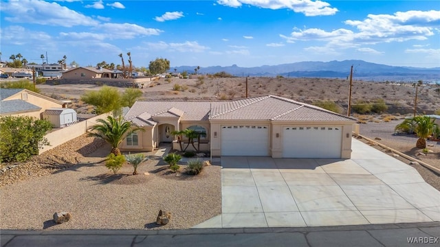 view of front of property with a mountain view, a tiled roof, an attached garage, and stucco siding