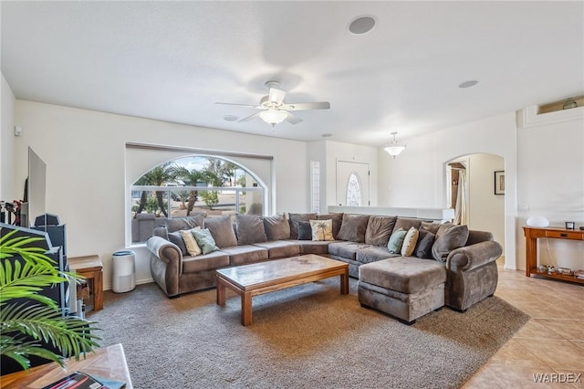 living room with arched walkways, ceiling fan, and light tile patterned floors