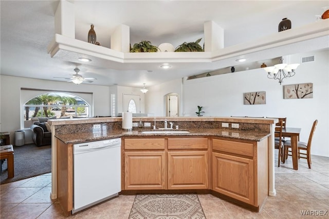 kitchen with a sink, dark stone counters, dishwasher, and open floor plan