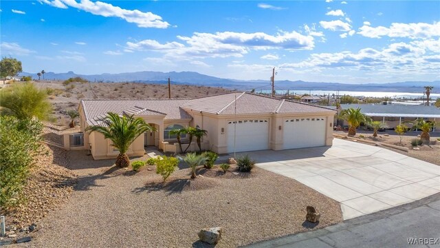 view of front of house with concrete driveway, a tiled roof, an attached garage, a mountain view, and stucco siding