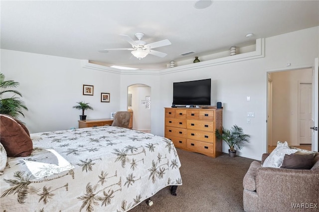 carpeted bedroom featuring arched walkways, visible vents, and ceiling fan