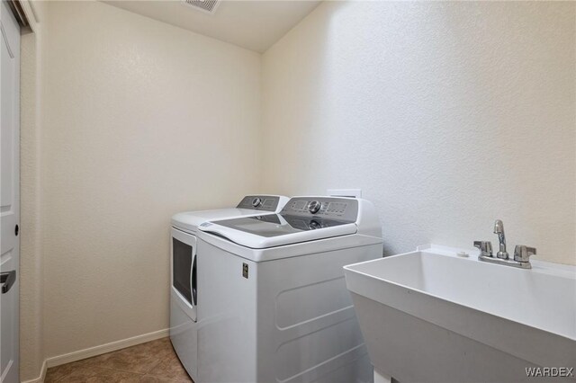 washroom with washing machine and clothes dryer, light tile patterned floors, a sink, laundry area, and baseboards