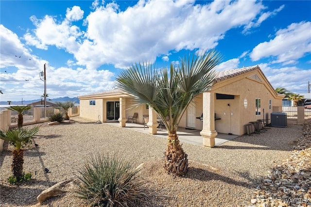 rear view of house with central air condition unit, a patio area, fence, and stucco siding