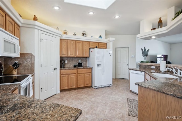 kitchen featuring white appliances, dark stone countertops, a sink, backsplash, and recessed lighting