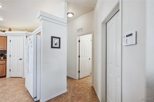 corridor featuring light tile patterned floors, baseboards, and visible vents