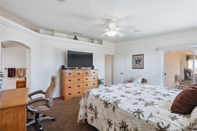 carpeted bedroom with a ceiling fan, arched walkways, and visible vents