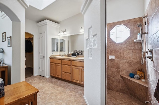 bathroom featuring tile patterned flooring, a spacious closet, a walk in shower, and vanity