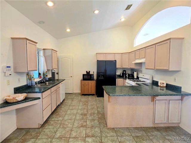 kitchen featuring dark countertops, a sink, high vaulted ceiling, black appliances, and a peninsula
