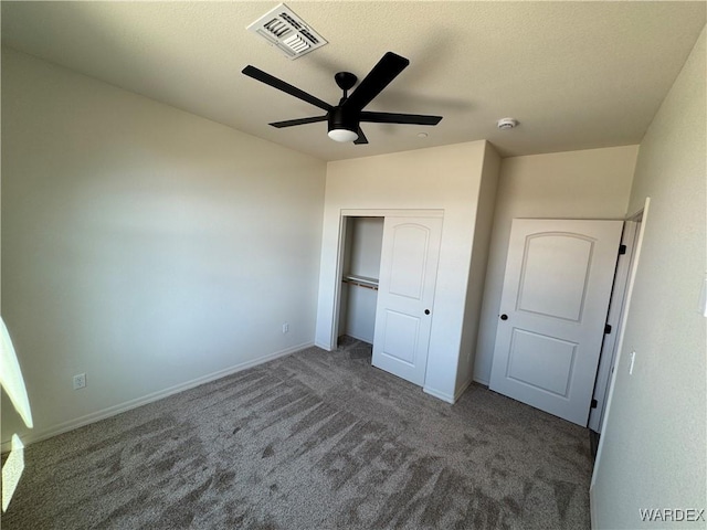 unfurnished bedroom with baseboards, visible vents, a ceiling fan, dark colored carpet, and a closet