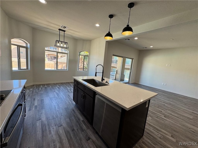 kitchen with an island with sink, pendant lighting, a sink, and light countertops