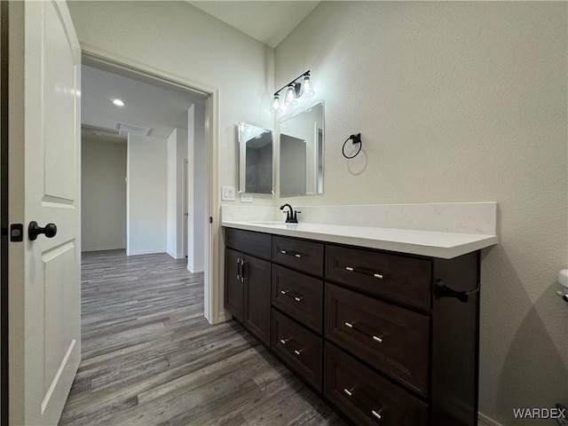 bathroom with wood finished floors, vanity, and baseboards