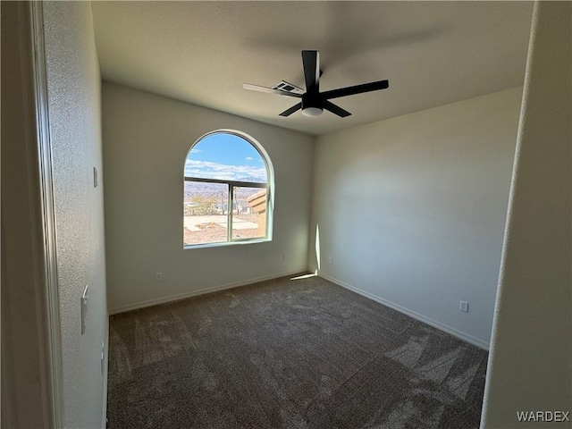 spare room featuring a ceiling fan, dark colored carpet, visible vents, and baseboards