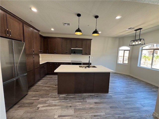 kitchen featuring appliances with stainless steel finishes, pendant lighting, light countertops, and a sink