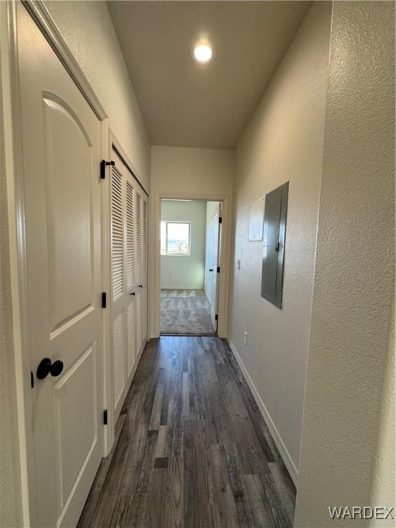 hallway featuring dark wood-style flooring, electric panel, a textured wall, and baseboards