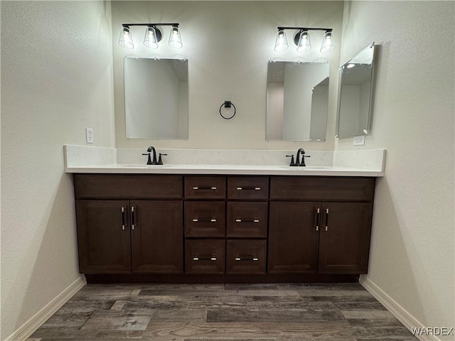 full bathroom featuring double vanity, a sink, and wood finished floors