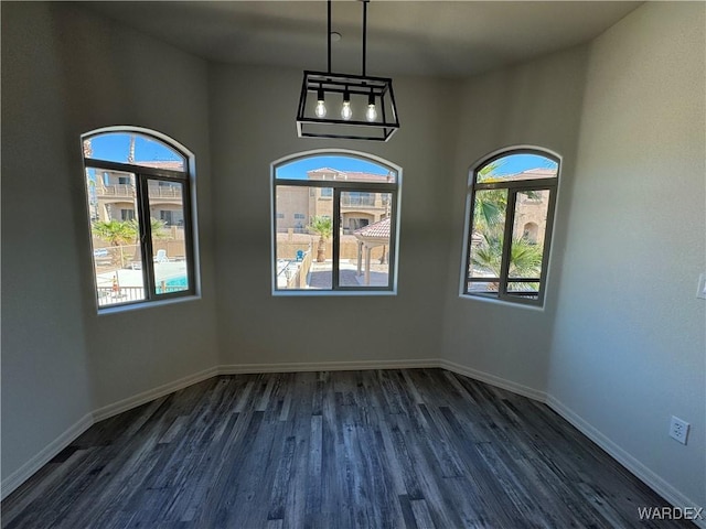 unfurnished room featuring baseboards and dark wood-type flooring