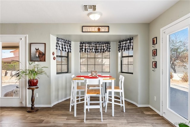 dining area with visible vents, baseboards, and wood finished floors