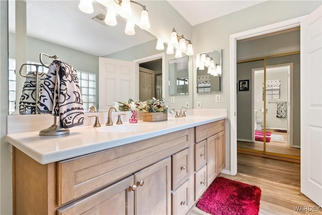 full bath featuring double vanity, wood finished floors, a sink, and visible vents