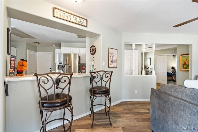 kitchen featuring a peninsula, a breakfast bar, stainless steel refrigerator with ice dispenser, and a ceiling fan