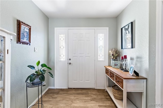 foyer entrance with baseboards and wood finished floors