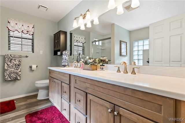 bathroom featuring a shower stall, visible vents, a sink, and wood finished floors