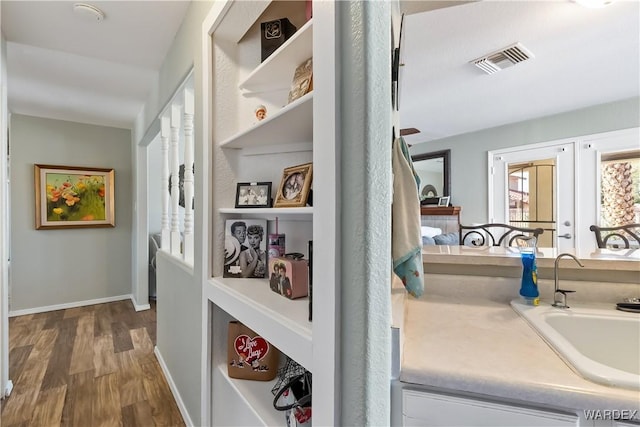 corridor with baseboards, visible vents, dark wood-type flooring, french doors, and a sink