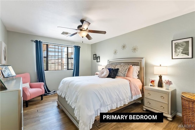 bedroom with ceiling fan, visible vents, and wood finished floors