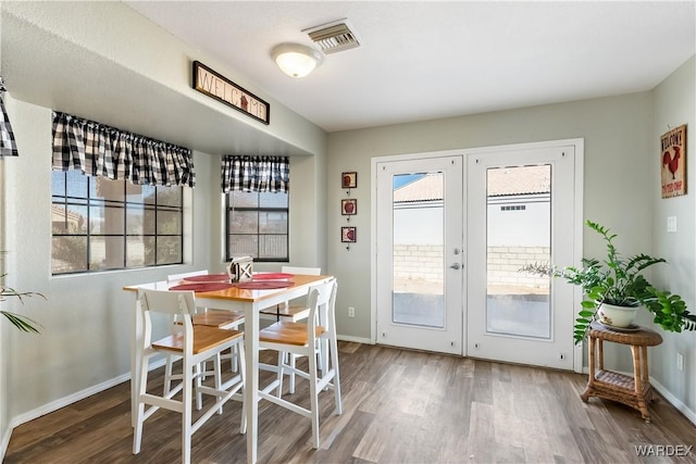 dining room with french doors, wood finished floors, visible vents, and baseboards