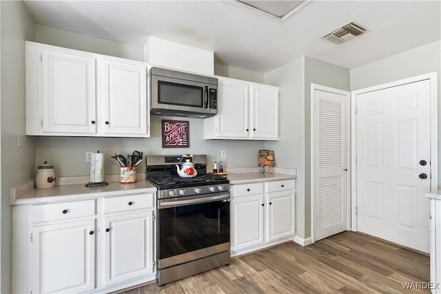 kitchen featuring stainless steel appliances, light wood-type flooring, visible vents, and white cabinets