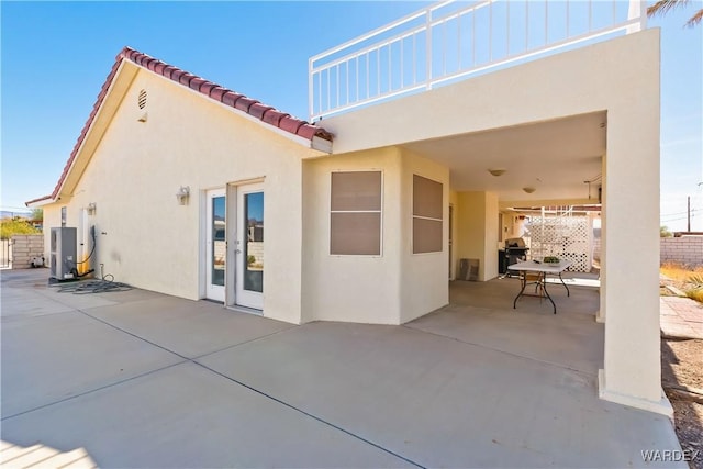 back of property featuring a patio, a tiled roof, fence, french doors, and stucco siding