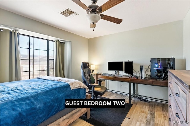 bedroom with a ceiling fan, visible vents, and wood finished floors