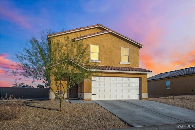 traditional home with a garage, concrete driveway, a tile roof, and stucco siding