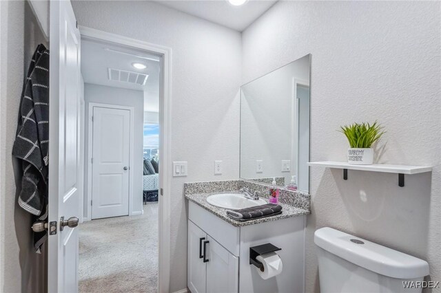 bathroom with visible vents, a textured wall, toilet, ensuite bathroom, and vanity