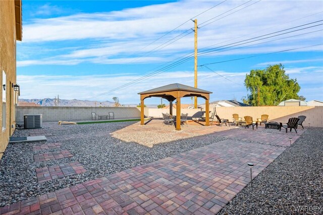 view of patio with a fenced backyard, a mountain view, a gazebo, and central AC unit