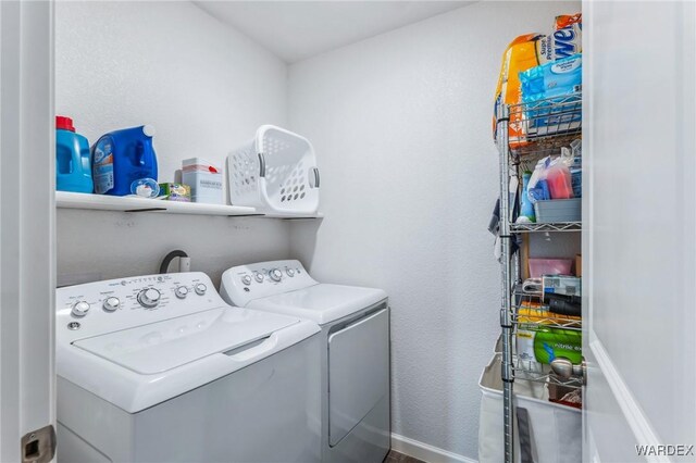 washroom featuring laundry area, separate washer and dryer, and baseboards