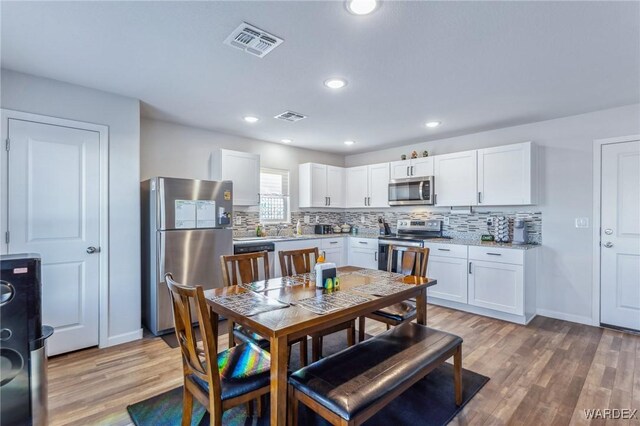 kitchen featuring stainless steel appliances, white cabinetry, light wood-style floors, and visible vents