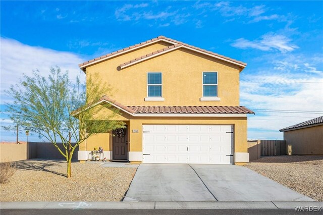 view of front of house featuring driveway, a tiled roof, fence, and stucco siding