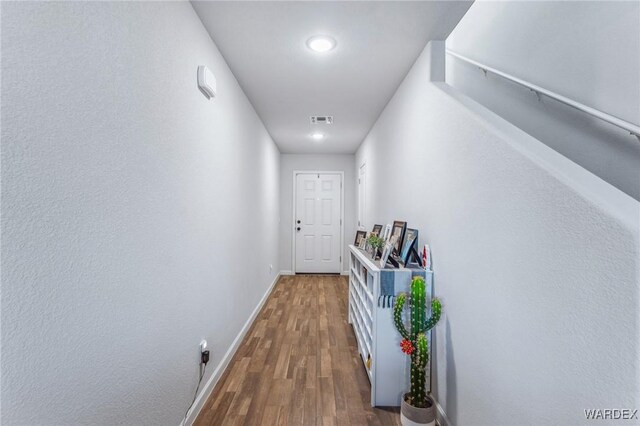 hall with visible vents, dark wood finished floors, and baseboards