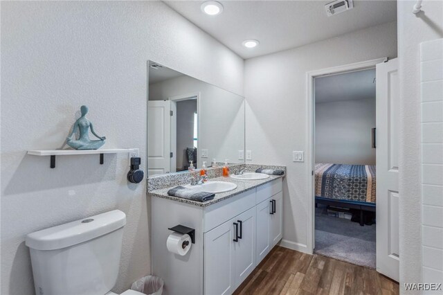 ensuite bathroom featuring visible vents, toilet, a sink, ensuite bath, and wood finished floors