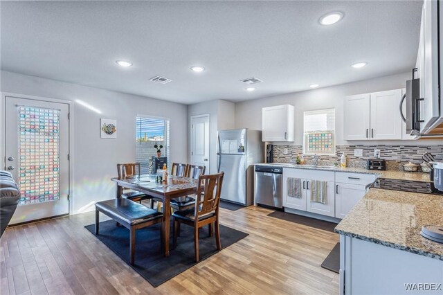 kitchen featuring visible vents, white cabinetry, stainless steel appliances, and light stone counters