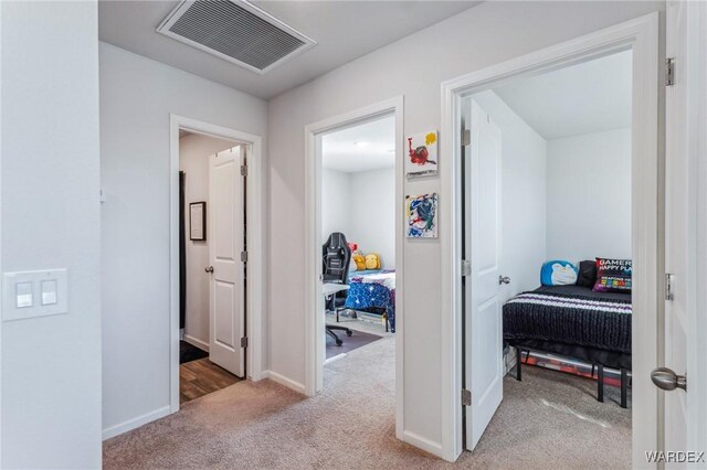 hallway featuring carpet floors, visible vents, and baseboards