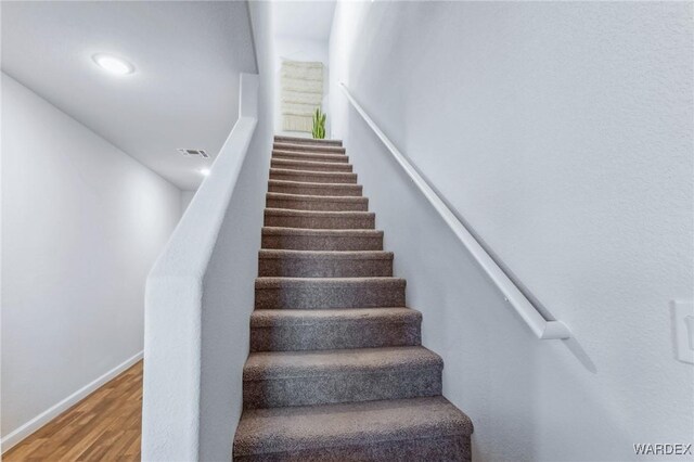 stairway with wood finished floors, visible vents, and baseboards