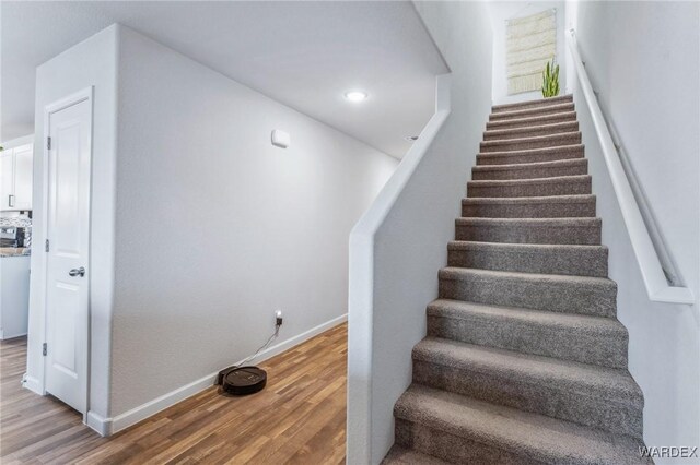 stairway with recessed lighting, baseboards, and wood finished floors