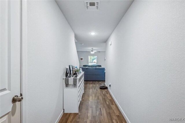 hall featuring dark wood-style floors, visible vents, and baseboards