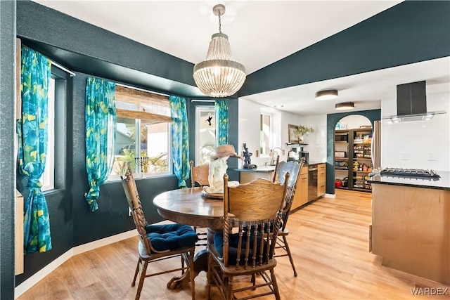 dining space with baseboards, an inviting chandelier, and light wood-style floors