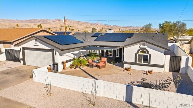 ranch-style house featuring concrete driveway, an attached garage, fence private yard, a mountain view, and stucco siding