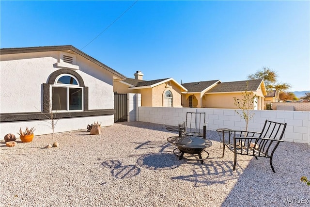 back of property with an outdoor fire pit, fence, a patio, and stucco siding