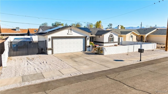 ranch-style home featuring a fenced front yard, stucco siding, roof mounted solar panels, a garage, and driveway