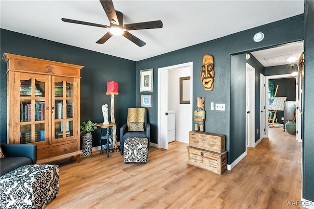 sitting room with ceiling fan, baseboards, and wood finished floors